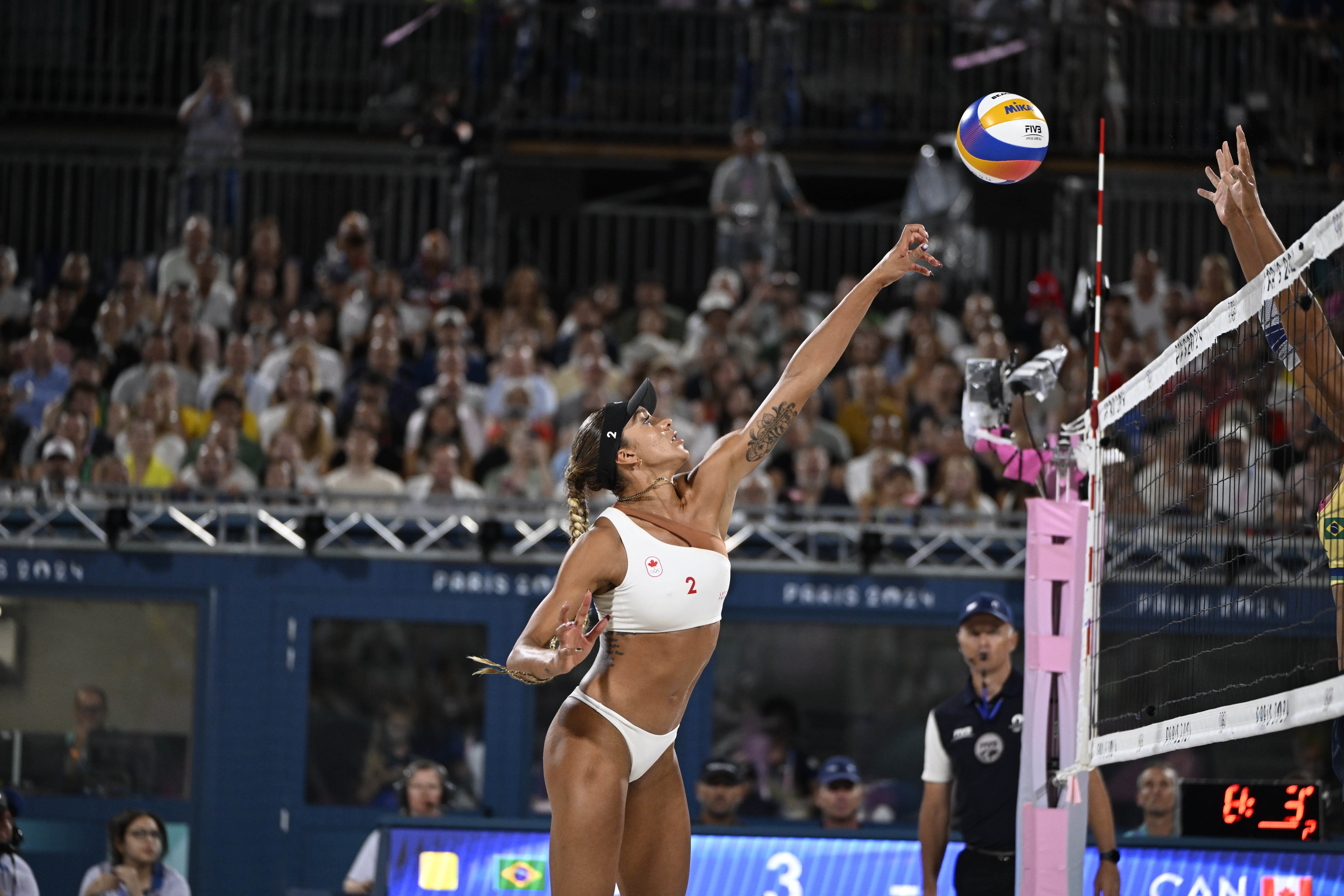 Canadian beach volleyball player at the Olympics, jumping up to hit a shot over the net Canadian beach volleyball player at the Olympics, jumping up to hit a shot over the net